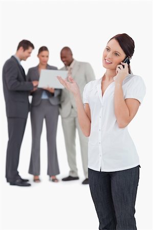 simsearch:400-06686555,k - Tradeswoman on the phone with colleagues behind her against a white background Stock Photo - Budget Royalty-Free & Subscription, Code: 400-06685394