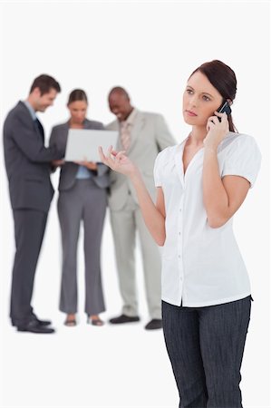 simsearch:400-06686555,k - Businesswoman on the phone with colleagues behind her against a white background Stock Photo - Budget Royalty-Free & Subscription, Code: 400-06685393