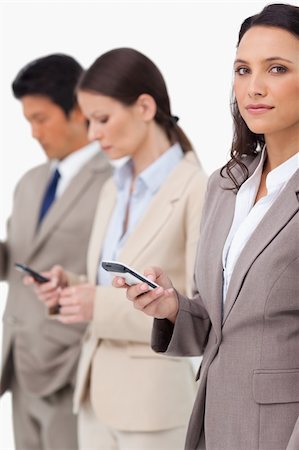 simsearch:400-06686562,k - Businesswoman with cellphone next to colleagues against a white background Foto de stock - Super Valor sin royalties y Suscripción, Código: 400-06685524