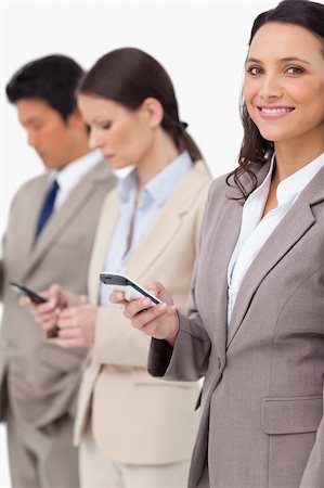 simsearch:400-06686555,k - Smiling businesswoman with cellphone next to colleagues against a white background Stock Photo - Budget Royalty-Free & Subscription, Code: 400-06685525