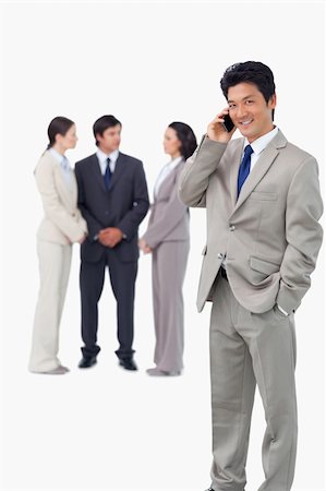 simsearch:400-06686562,k - Businessman on cellphone with colleagues behind him against a white background Foto de stock - Super Valor sin royalties y Suscripción, Código: 400-06685556