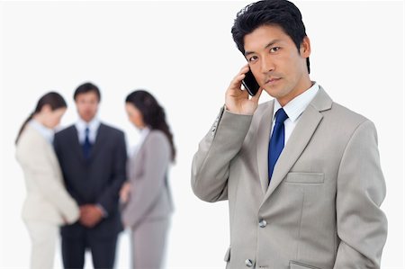 simsearch:400-06686555,k - Serious businessman on cellphone with team behind him against a white background Stock Photo - Budget Royalty-Free & Subscription, Code: 400-06685558