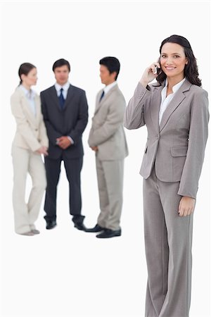 simsearch:400-06686555,k - Smiling saleswoman on her cellphone with team behind her against a white background Stock Photo - Budget Royalty-Free & Subscription, Code: 400-06686480