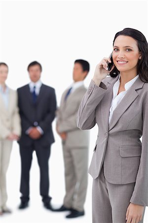 simsearch:400-06686562,k - Smiling saleswoman on cellphone with team behind her against a white background Foto de stock - Super Valor sin royalties y Suscripción, Código: 400-06686482