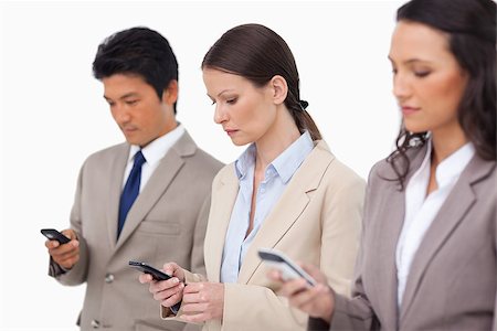 simsearch:400-06686555,k - Salesteam looking at their cellphones against a white background Stock Photo - Budget Royalty-Free & Subscription, Code: 400-06686548