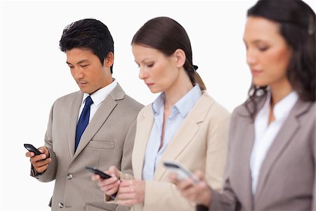 simsearch:400-06686555,k - Young businessteam with their cellphones against a white background Stock Photo - Budget Royalty-Free & Subscription, Code: 400-06686549