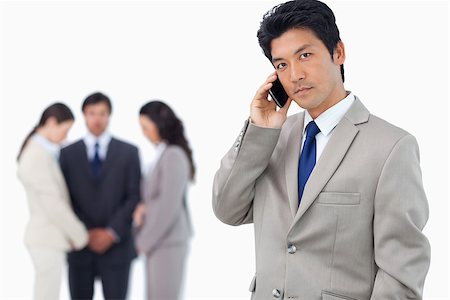simsearch:400-06393704,k - Serious businessman on cellphone with team behind him against a white background Stock Photo - Budget Royalty-Free & Subscription, Code: 400-06686555
