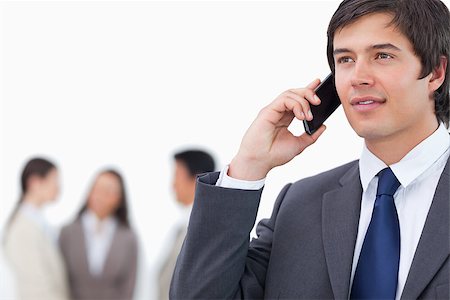 simsearch:400-06686555,k - Salesman on his cellphone with team behind him against a white background Stock Photo - Budget Royalty-Free & Subscription, Code: 400-06686558