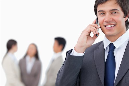 simsearch:400-06686555,k - Smiling salesman on his cellphone with team behind him against a white background Stock Photo - Budget Royalty-Free & Subscription, Code: 400-06686559