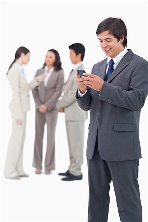 simsearch:400-06686562,k - Smiling salesman holding mobile phone with team behind him against a white background Foto de stock - Super Valor sin royalties y Suscripción, Código: 400-06686564