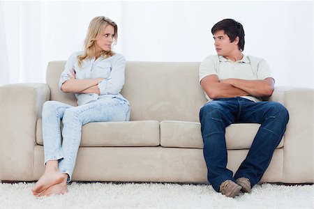 simsearch:400-06687238,k - A angry couple sit at the two ends of the couch with their arms folded looking at each other Fotografie stock - Microstock e Abbonamento, Codice: 400-06687237
