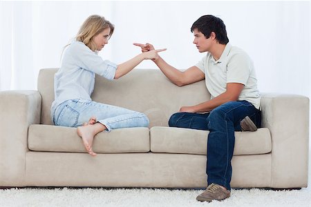 simsearch:400-06687238,k - A couple sitting on a couch are looking at each other and pointing Fotografie stock - Microstock e Abbonamento, Codice: 400-06687239