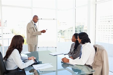 Businessman pointing to something on the flipchart to give explanations to his team Stock Photo - Budget Royalty-Free & Subscription, Code: 400-06688574