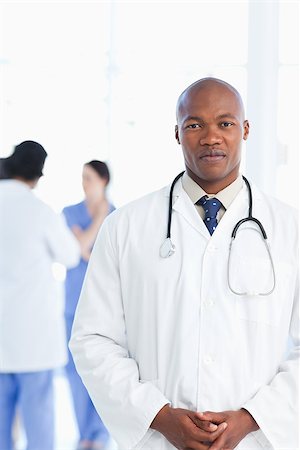 Doctor standing upright with his hands crossed with his medical team standing behind him Stock Photo - Budget Royalty-Free & Subscription, Code: 400-06688586