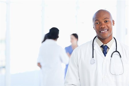 Doctor standing in a well-lit room with his team in the background Stock Photo - Budget Royalty-Free & Subscription, Code: 400-06688588