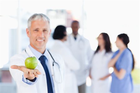 Smiling mature doctor holding an apple Stock Photo - Budget Royalty-Free & Subscription, Code: 400-06688595