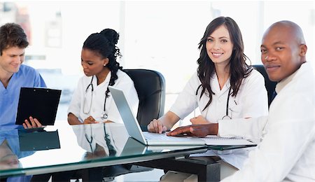 Members of a medical tean looking at the camera while working on a laptop Stock Photo - Budget Royalty-Free & Subscription, Code: 400-06688615