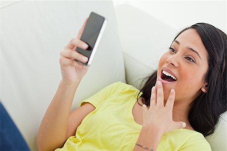 Close-up of a surprised Latino woman looking her smartphone while lying on a sofa Stock Photo - Budget Royalty-Free & Subscription, Code: 400-06688671