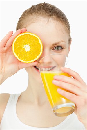 simsearch:400-06689686,k - Woman placing an orange on her eye while drinking in a glass against white background Foto de stock - Super Valor sin royalties y Suscripción, Código: 400-06689848