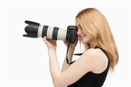 people holding camera slr - Woman smiling while holding a SLR camera against white background Stock Photo - Budget Royalty-Free & Subscription, Code: 400-06689938