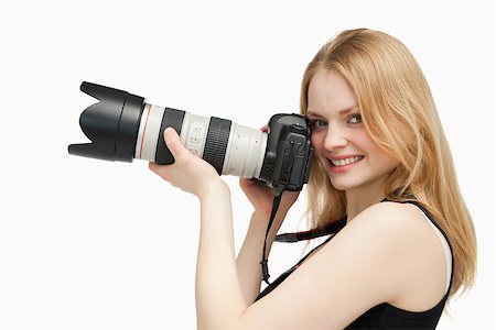 people holding camera slr - Woman looking at the camera while holding a camera against white background Stock Photo - Budget Royalty-Free & Subscription, Code: 400-06689939