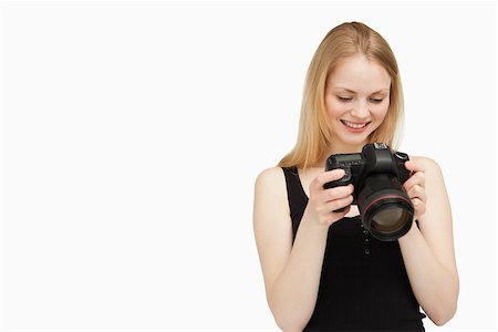 people holding camera slr - Cheerful woman looking at her camera against white background Stock Photo - Budget Royalty-Free & Subscription, Code: 400-06689930