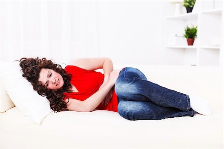 Girl lying on the sofa with stomach ache Foto de stock - Royalty-Free Super Valor e Assinatura, Número: 400-06694212