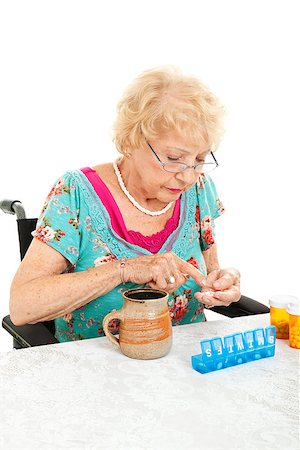 pillbox - Disabled senior woman in wheelchair counting her pills into a pill container for the week.  White background. Stock Photo - Budget Royalty-Free & Subscription, Code: 400-06695200