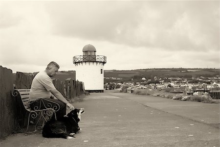 A mature man and his dog sitting by a light house Stock Photo - Budget Royalty-Free & Subscription, Code: 400-06695299