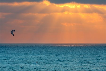 Lone kitesurfer glides on wavy water surface against background of beautiful cloudy sky at sunset on Mediterranean sea in Israel. Stock Photo - Budget Royalty-Free & Subscription, Code: 400-06698093