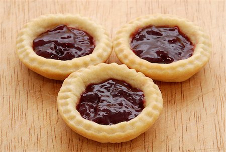 simsearch:400-06693299,k - Three tasty jam tarts sitting on a wooden table Stockbilder - Microstock & Abonnement, Bildnummer: 400-06699659