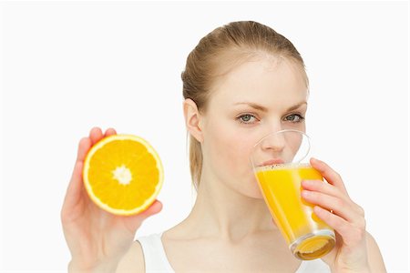 simsearch:400-06689686,k - Woman presenting an orange while drinking against white background Foto de stock - Super Valor sin royalties y Suscripción, Código: 400-06690085