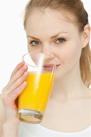 simsearch:400-06689686,k - Woman drinking a glass of orange juice against white background Foto de stock - Super Valor sin royalties y Suscripción, Código: 400-06690102