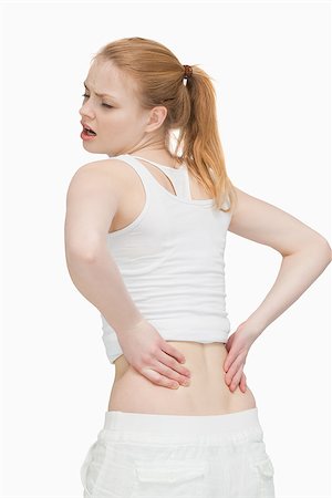 simsearch:400-06690149,k - Young woman massaging her back against white background Stock Photo - Budget Royalty-Free & Subscription, Code: 400-06690138