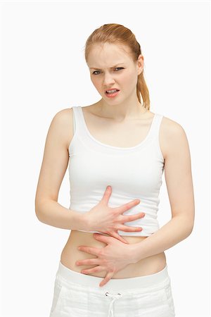 simsearch:400-06690149,k - Suffering woman placing her hands on her stomach against white background Stock Photo - Budget Royalty-Free & Subscription, Code: 400-06690132