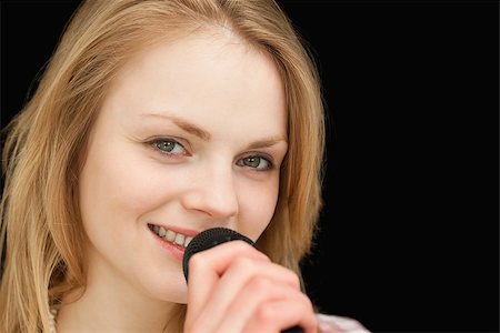 Young woman smiling while singing against black background Stock Photo - Budget Royalty-Free & Subscription, Code: 400-06690159