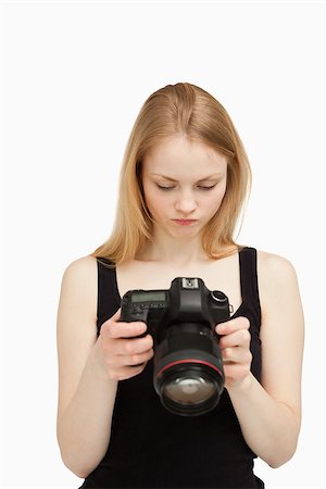 people holding camera slr - Woman looking at the screen of her camera against white background Stock Photo - Budget Royalty-Free & Subscription, Code: 400-06690237