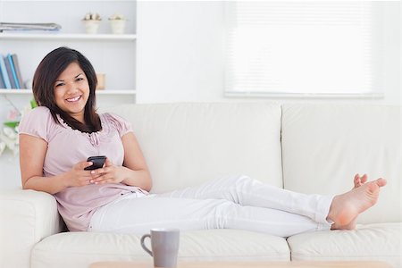 Woman smiling and lying on a couch in a living room Stock Photo - Budget Royalty-Free & Subscription, Code: 400-06690244