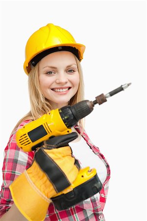 Woman smiling while holding an electric screwdriver against white background Photographie de stock - Aubaine LD & Abonnement, Code: 400-06690309