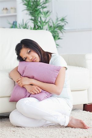Woman looking sad while holding a pillow in a living room Stock Photo - Budget Royalty-Free & Subscription, Code: 400-06690619