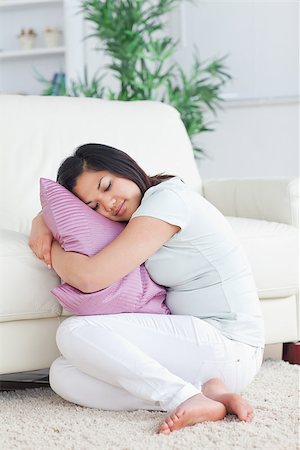 Sleeping woman holding a pillow while sitting on the floor in a living room Stock Photo - Budget Royalty-Free & Subscription, Code: 400-06690621