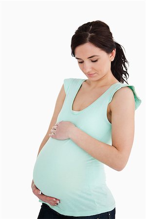 simsearch:400-06690931,k - Young pregnant woman looking at her belly against white background Fotografie stock - Microstock e Abbonamento, Codice: 400-06690927