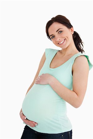 simsearch:400-06690931,k - Young pregnant woman smiling at camera against white background Fotografie stock - Microstock e Abbonamento, Codice: 400-06690928