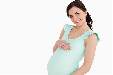 simsearch:400-06690931,k - Pregnant woman smiling against white background Fotografie stock - Microstock e Abbonamento, Codice: 400-06690929