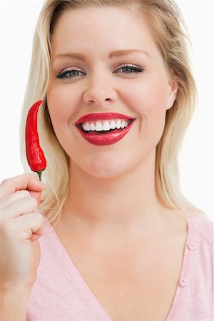 simsearch:400-04575822,k - Cheerful blonde woman showing a chili against a white background Photographie de stock - Aubaine LD & Abonnement, Code: 400-06691485