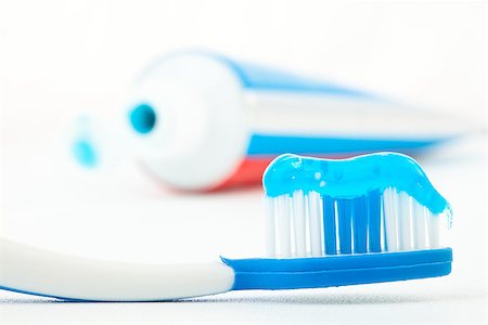 Toothbrush with blue toothpaste next to a tube of toothpaste against white background Stock Photo - Budget Royalty-Free & Subscription, Code: 400-06691711