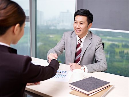 a smiling asian business executive shaking hands with his female colleague in office. Stock Photo - Budget Royalty-Free & Subscription, Code: 400-06691796