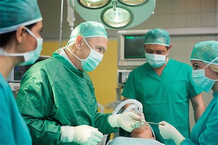 simsearch:400-06734621,k - Smiling surgeon working with a team in a surgical room Stock Photo - Budget Royalty-Free & Subscription, Code: 400-06734000