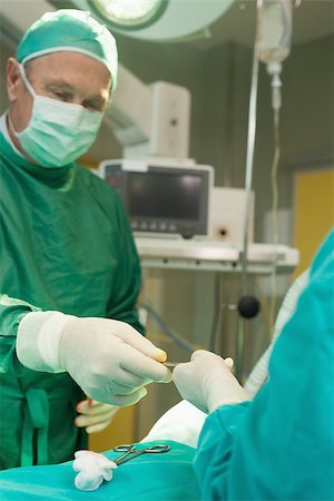 simsearch:400-06734621,k - Surgeon holding scalpel during an operation in a surgical room Stock Photo - Budget Royalty-Free & Subscription, Code: 400-06734060