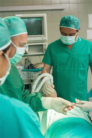 simsearch:400-06734621,k - Medical team taking a scalpel from the hand of a colleague in a surgical room Stock Photo - Budget Royalty-Free & Subscription, Code: 400-06734061